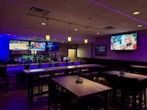 Stylish sports bar and lounge at Strikers Bowling, featuring high-top tables, a full bar, and Bowling Specials & Deals in Sunrise, FL.