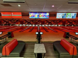 Modern Best Bowling in Sunrise FL with red-themed lanes, digital scoreboards, and stylish seating area with black and red couches.