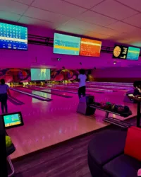 Glow Bowling Night at Strikers – Neon Lights & Fun Atmosphere Best Bowling in Sunrise FL with neon purple lighting, digital scoreboards, and players enjoying a game at Strikers Bowling Alley.