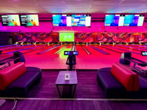 A stylish and modern bowling lane at Strikers Bowling in Sunrise, FL, featuring glowing lane lights, comfortable lounge seating, and interactive scoreboards.