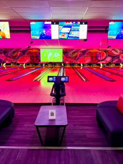 A stylish and modern bowling lane at Strikers Bowling in Sunrise, FL, featuring glowing lane lights, comfortable lounge seating, and interactive scoreboards.