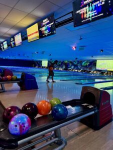 Best Bowling in Sunrise FL with vibrant lighting, colorful bowling balls, and digital scoreboards displaying game information at Strikers Bowling.