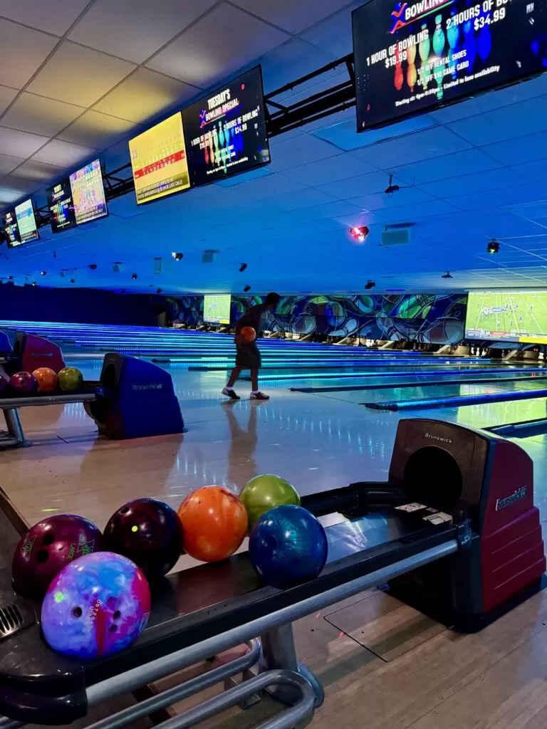 Best Bowling in Sunrise FL with vibrant lighting, colorful bowling balls, and digital scoreboards displaying game information at Strikers Bowling.