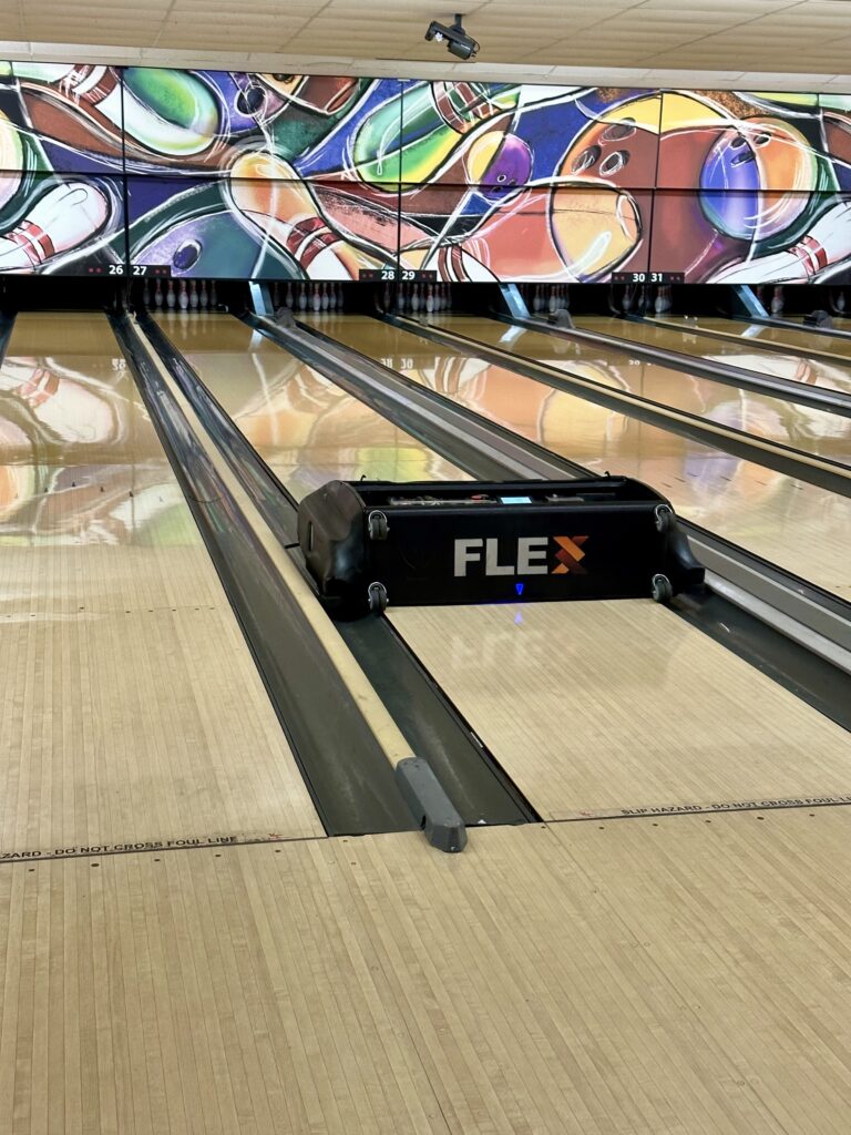 A lane conditioning machine applying oil to a bowling lane, ensuring optimal lane conditions for league and competitive bowlers