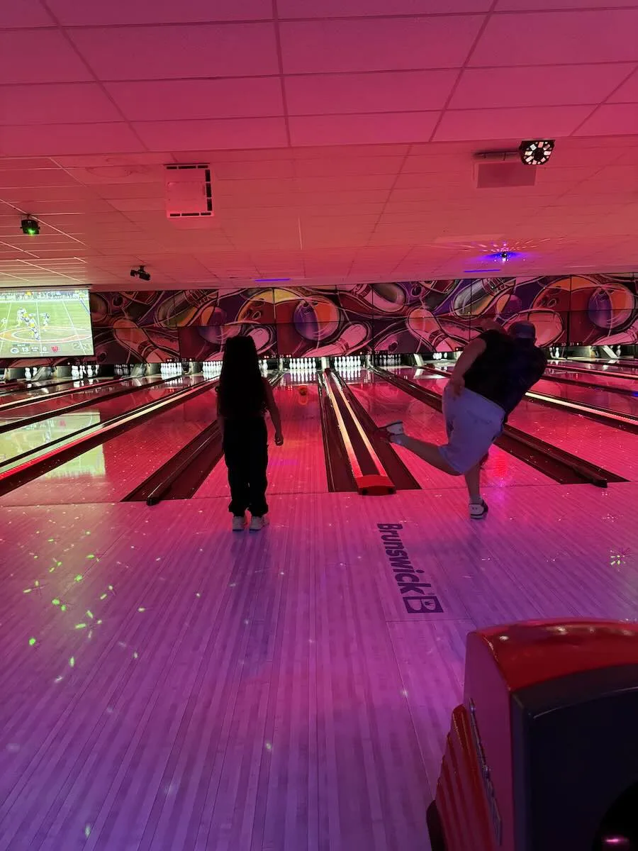 Family Cosmic Bowling at Strikers Sunrise Family enjoying cosmic bowling at Strikers Sunrise as a bowler releases a shot on illuminated lanes under colorful LED lighting in Sunrise, Florida.