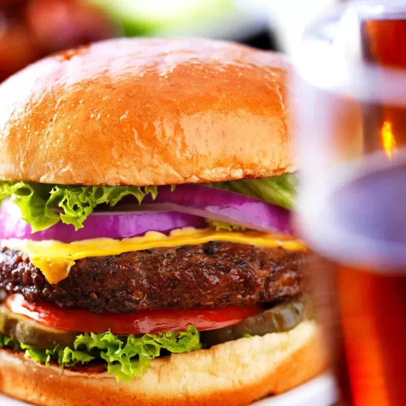 Juicy Cheeseburger & Cold Beer – Strikers Bowling Bar & Grill Delicious gourmet cheeseburger with fresh lettuce, tomato, onion, and melted cheese on a toasted bun, served with a cold beer.